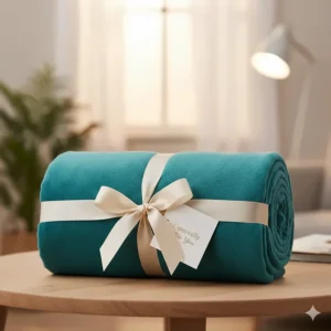 A rolled-up teal throw blanket tied with a ribbon, showing an affordable gift idea for under £50.