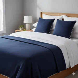 A navy blue bedspread layered over white linen on a double bed with matching cushions.