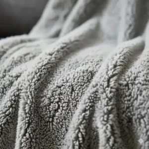 Close-up detail of the thick, white woolly texture of a soft sherpa fleece blanket.