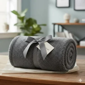 A rolled teddy fleece blanket tied with a grey grosgrain ribbon, perfect for a winter gift.