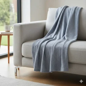 A thin, breathable cotton throw folded on a sofa, ideal for cool British summer evenings.