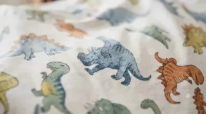 Close-up of ultra-soft fleece material on a boys dinosaur blanket showing the detailed prehistoric print.