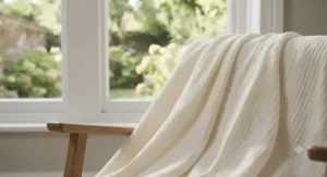 A breathable blanket folded neatly on a chair, showcasing its all-season temperature-regulating capabilities for warm British summer nights.