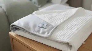 A lightweight double-sided cooling blanket folded neatly on an armchair in a stylish UK bedroom.