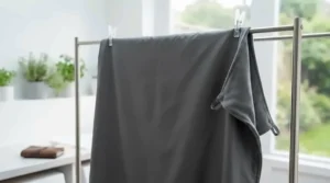 A quick-drying lightweight travel blanket hanging on a washing line, demonstrating easy machine-washable care for travel.