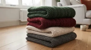 A curated selection of chunky knit Christmas throws folded in festive British winter colours including forest green and winter white.