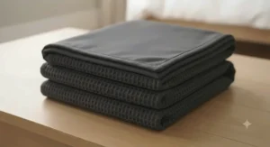 Modern charcoal grey cooling blanket folded neatly on crisp white bed linen to suit contemporary UK interior palettes.