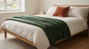 A rich red chunky knit Christmas throw styled across the foot of a winter-themed bed with linen bedding.