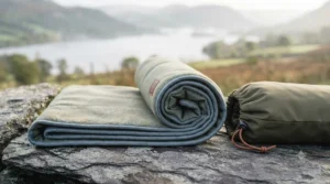 Step-by-step demonstration showing how to easily roll and pack a lightweight camping blanket into its stuff sack for backpacking.