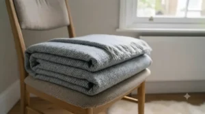 A breathable lightweight summer blanket folded neatly on a neutral armchair, illustrating cool comfort for warmer nights.