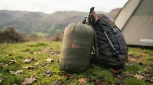 An insulated camping blanket packed down into its compact stuff sack next to a rucksack, ready for a weekend hiking trip in the Lake District.