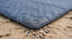 Close-up of a durable waterproof backing on a beach picnic blanket keeping sand and damp grass dry.