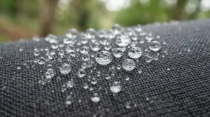 Water droplets beading on the surface of a durable camping blanket for festivals.